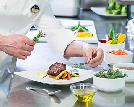 A chef garnishing a gourmet dish with fresh rosemary onboard | MSC Cruises