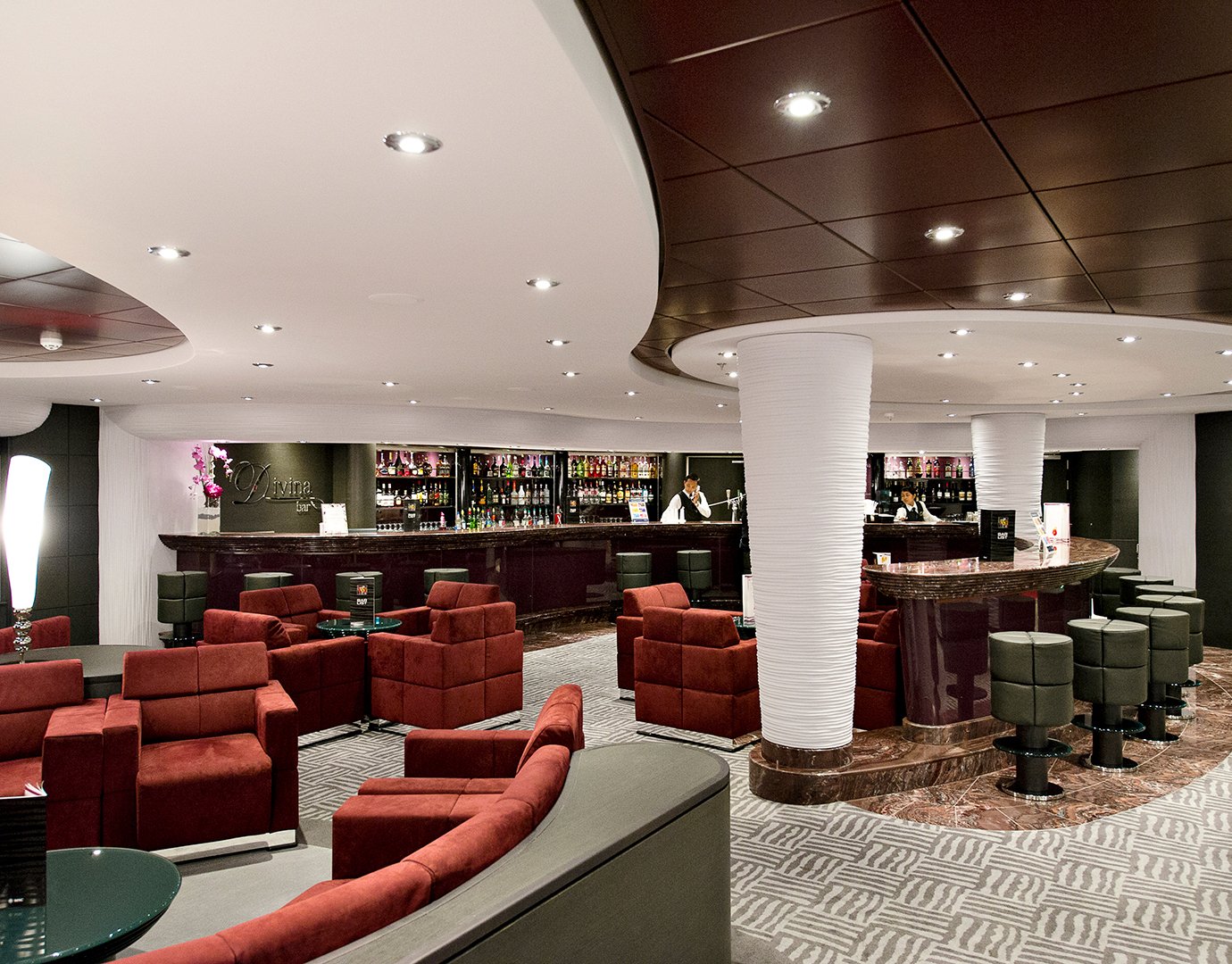 Elegant lounge with red armchairs and a modern bar onboard an MSC cruise ship | MSC Cruises Elegant lounge with red armchairs and a modern bar onboard an MSC cruise ship | MSC Cruises