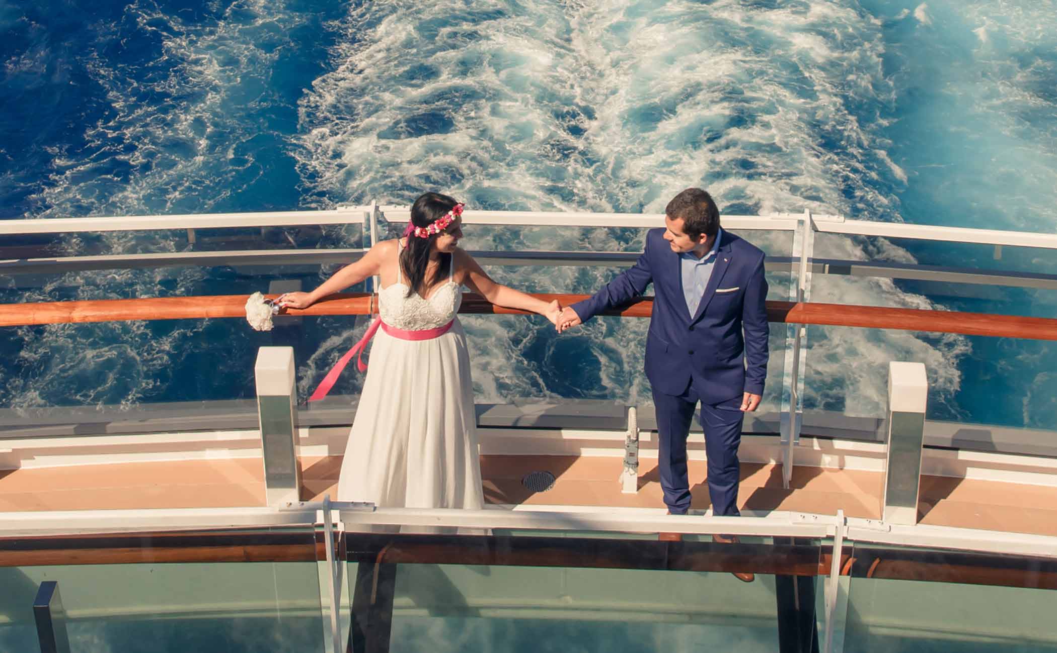 A couple holding hands on a cruise ship deck with ocean waves in the background | MSC Cruises A couple holding hands on a cruise ship deck with ocean waves in the background | MSC Cruises