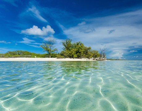 Crystal-clear waters and a tropical island under a vibrant blue sky | MSC Cruises