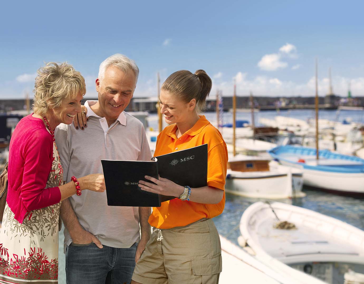 An MSC staff member assisting travelers with cruise information by a marina | MSC Cruises An MSC staff member assisting travelers with cruise information by a marina | MSC Cruises