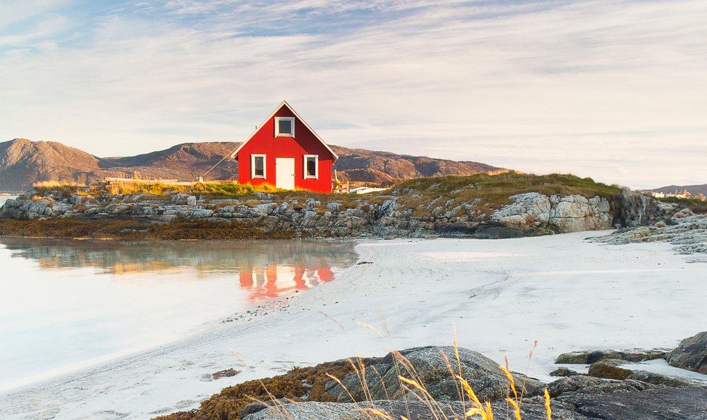 A red cabin on a rocky coastal landscape with white sand and calm waters | MSC Cruises