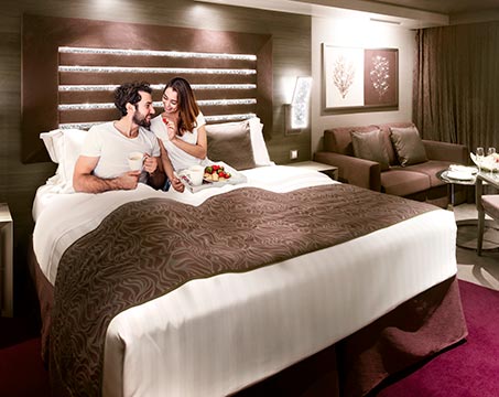 Couple enjoying a luxurious bed in an MSC cruise ship cabin | MSC Cruises Couple enjoying a luxurious bed in an MSC cruise ship cabin | MSC Cruises