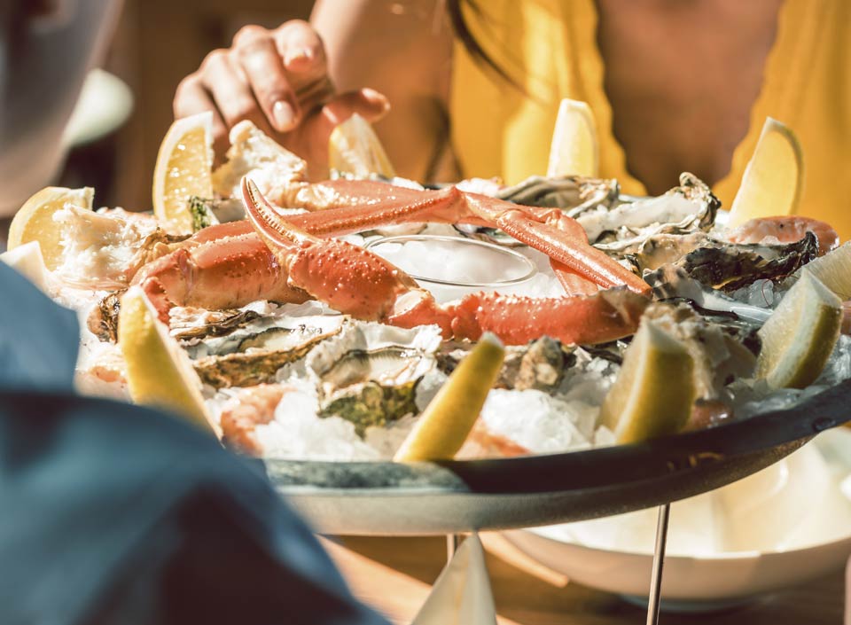 A seafood platter with crab legs, oysters, and lemon slices served onboard | MSC Cruises