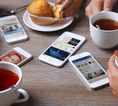 Smartphones on a table showing MSC Cruises apps and social media, with tea and muffins | MSC Cruises
