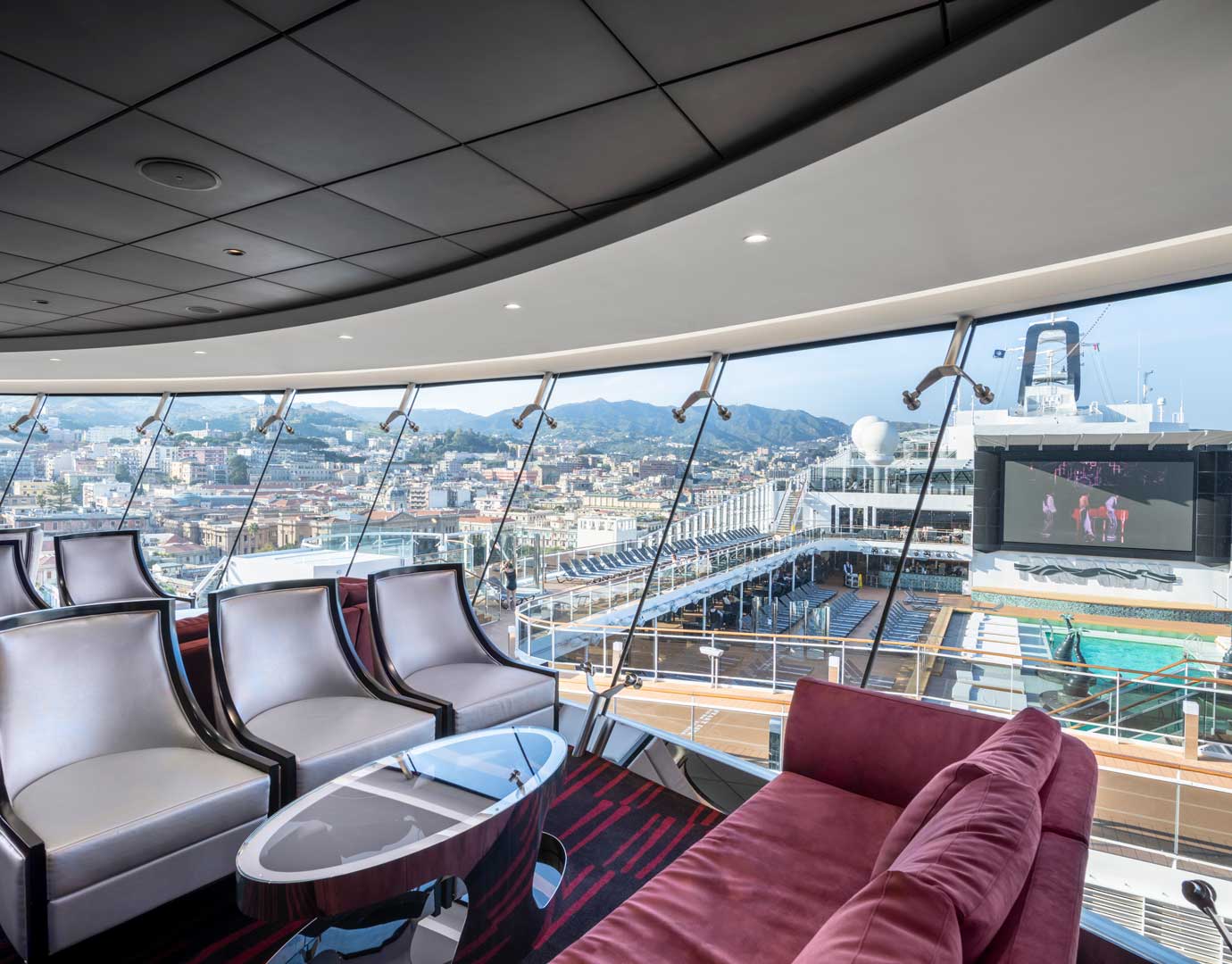 Luxurious lounge with panoramic views of a cruise ship and city skyline | MSC Cruises Luxurious lounge with panoramic views of a cruise ship and city skyline | MSC Cruises